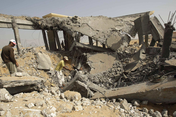 Palestinians survey building hit by an Israeli air strike