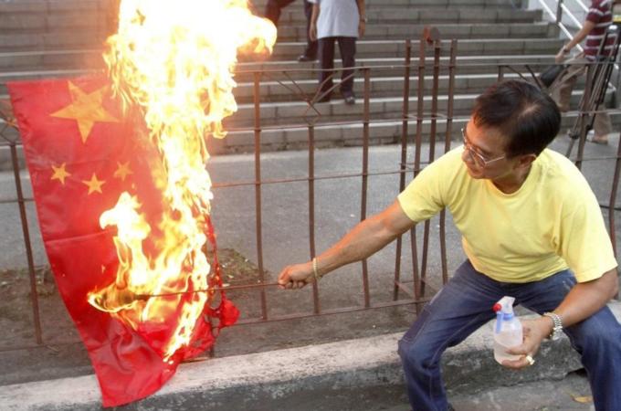 An activist burns a flag of China during a protest to demand that the Chinese government pull out from the Scarborough Shoal during a rally in front of the Chinese consular office in Makati''s financial district of Manila