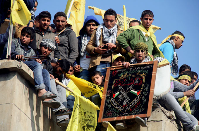 Young men in Gaza City hold the yellow flags of Fatah at a mass celebration of the faction''s 48th anniversary [Mustafa Ashqar/Al Jazeera]