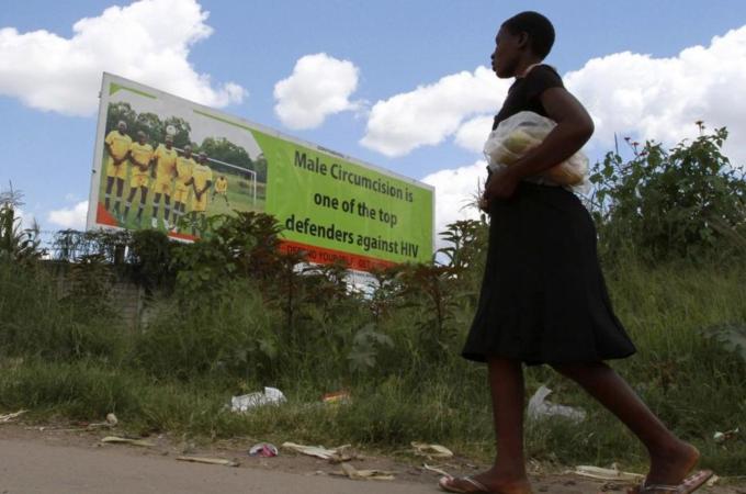 A Zimbabwean woman walks past a billboard promoting male circumcision to combat Aids in the capital