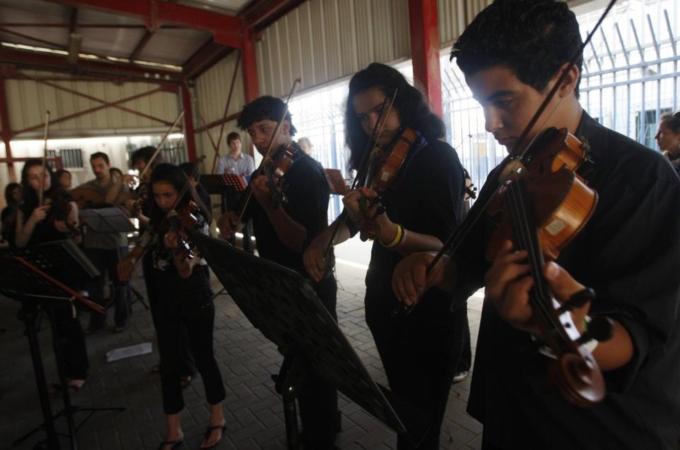 Palestinian students play their instruments during a joint performance with guest musicians at the Qalandiya checkpoint