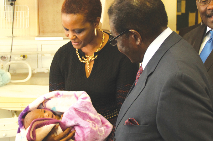 Mugabe and his wife Grace look at one of the twins at Harare Hospital [Gift Phiri/Al Jazeera]