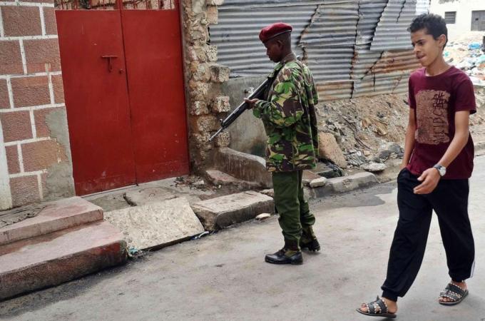 A young resident walks past an armed police officer at the scene of an attack on three Russian nationals, one of whom died, in Mombasa's old-town district in July [AFP]