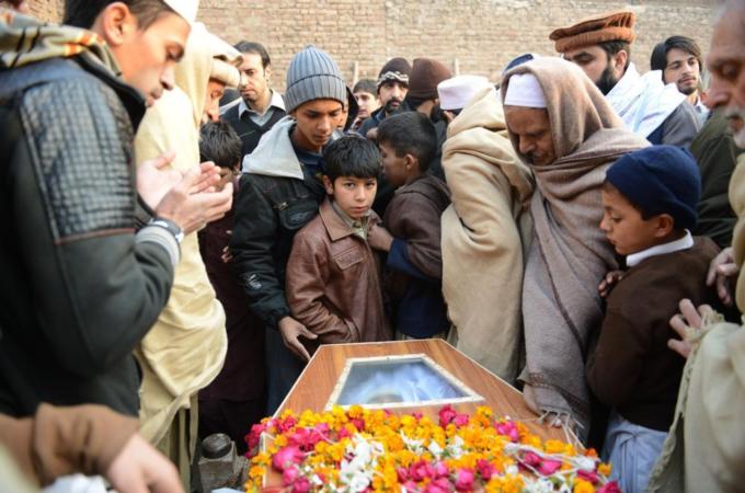 Pakistani mourners gather around a coffin during the funeral for a victim of an attack by Taliban militants [AFP]