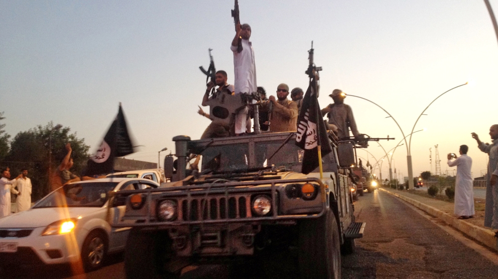 ISIL fighters parade in a commandeered Iraqi security forces armored vehicle down a main road in Mosul [AP]