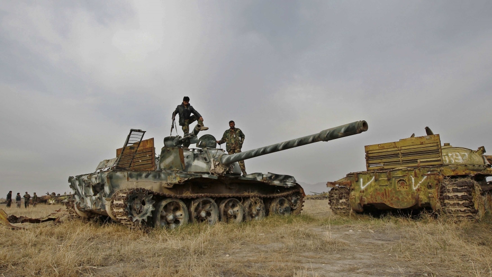 Members of Afghan security force inspect destroyed Soviet military tank at a junkyard in Jalalabad province