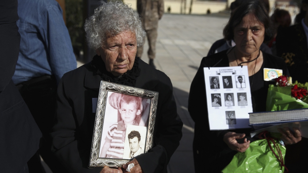 Greek Cypriot women hold photos of relatives missing since 1974 at Tymvos Macedonitissas military cemetery in Nicosia, during a visit by Greek PM Tsipras