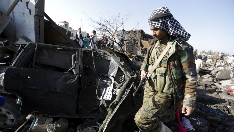 A Houthi fighter walks at the site of an air strike at a residential area near Sanaa Airport [REUTERS]