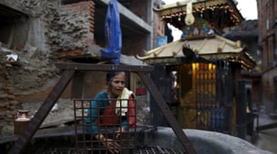 A woman fetches water from a well near a collapsed house in Nepal [REUTERS]
