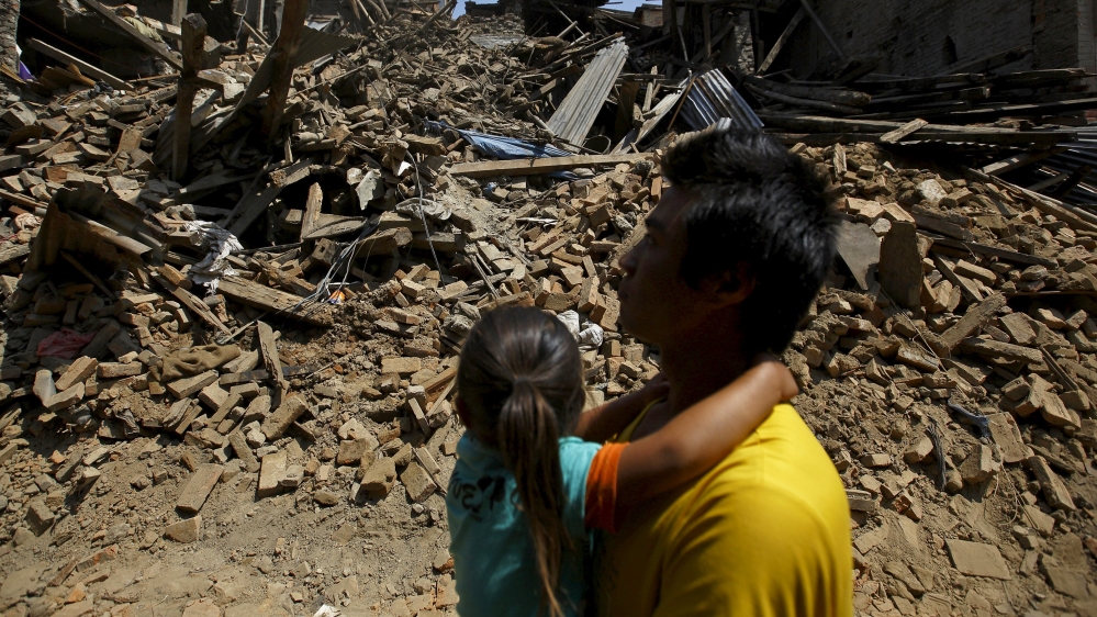 A man carrying a girl walks along the street near collapsed houses after last week''s earthquake in Bhaktapur