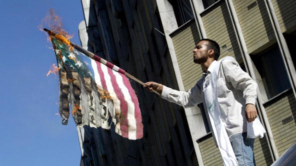 An Iranian hardliner wearing a death shroud burns a US flag outside the British embassy in Tehran in 2004 [Getty]