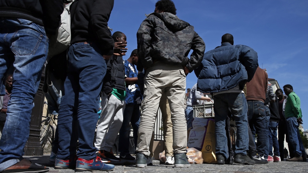 Migrants line up to receive food in front of the Saint-Bernard Church in Paris
