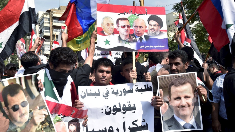 Syrians, living in Lebanon, carry banners as they wave Russian and Syrian national flags to express their support to Assad and to thank Russia for its intervention in Syria [REUTERS]
