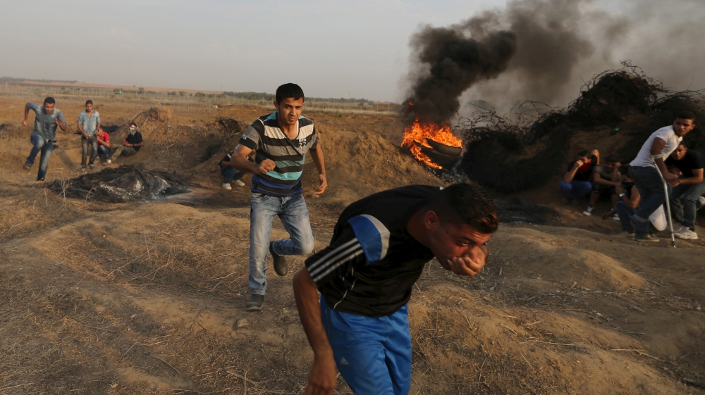Palestinian protesters run for cover during clashes with Israeli troops near the border between Israel and Central Gaza Strip