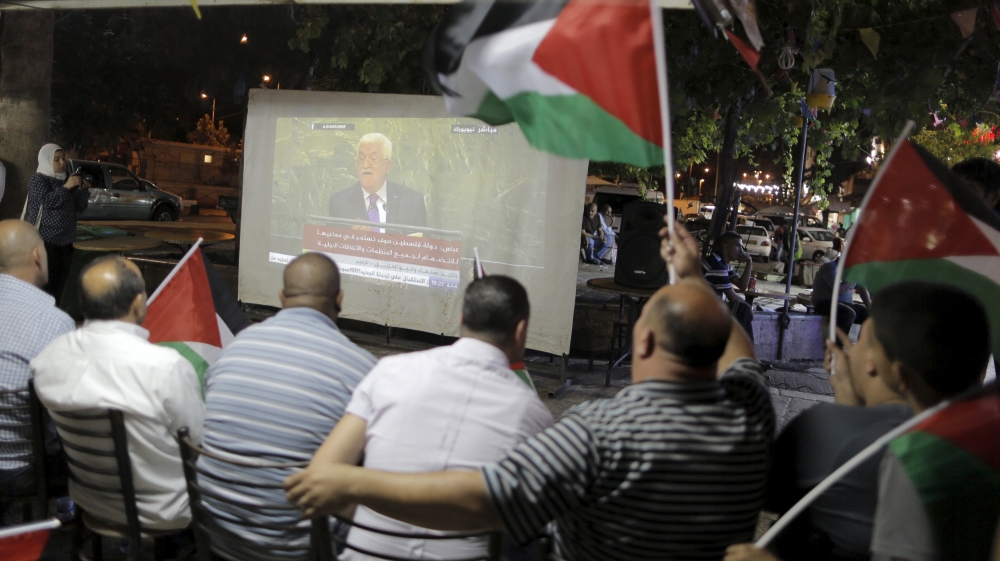 Palestinians wave Palestinian flags as they watch on a large screen the speech of Palestinian President Mahmoud Abbas near Damascus Gate, outside Jerusalem''s Old City