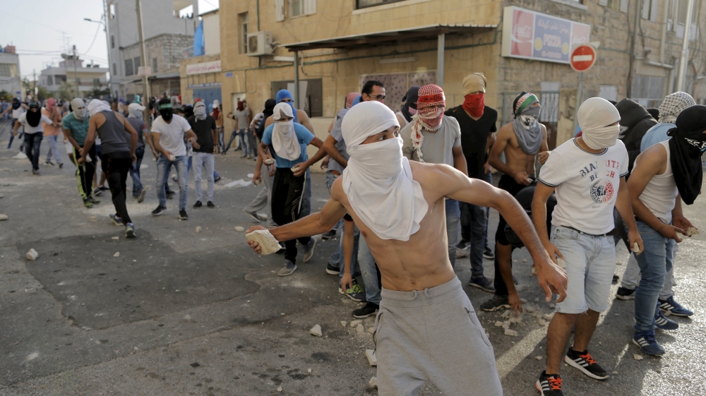 Palestinian protesters throw stones towards Israeli police during clashes in Shuafat, an Arab suburb of Jerusalem [REUTERS]