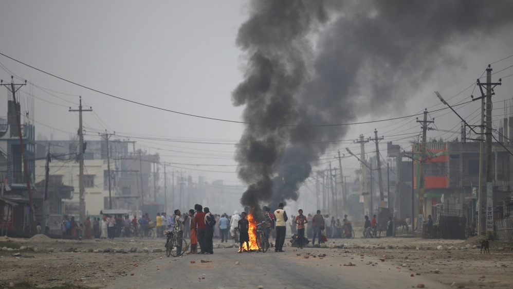 Protesters stand near burning tyres as they gather to block highway connecting Nepal and India, during general strike called by Madhesi protesters demonstrating against new constitution in Birgunj