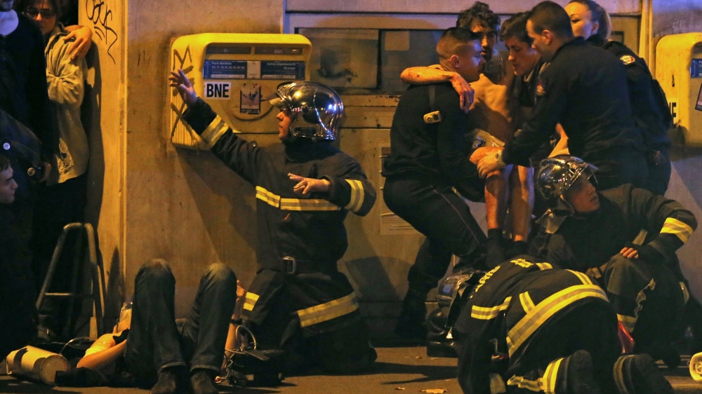 French fire brigade members aid an injured individual near the Bataclan concert hall following fatal shootings in Paris, France