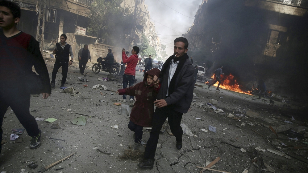 A man holds the hand of a girl as they rush away from a site hit by what activists said were airstrikes by forces loyal to Bashar al-Assad, in Damascus [REUTERS]