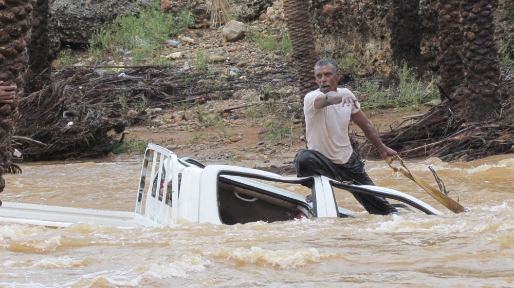 A man gestures as he tries to save a vehicle swept away by flood waters in Yemen''s island of Socotra