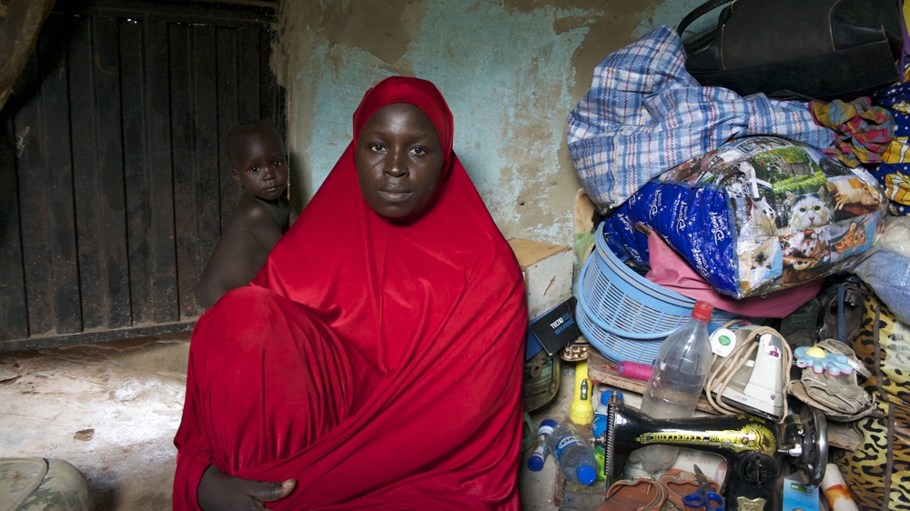 One-year-old Muhammadu plays at his mother's side in the room where she has helped more than 60 women from Gwoza give birth in the past year [Caelainn Hogan/Al Jazeera]