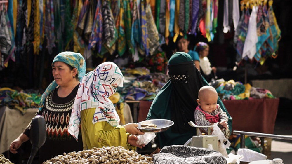 Uighur Muslim women trading food at the Turpan city market in Turpan, China [Getty]