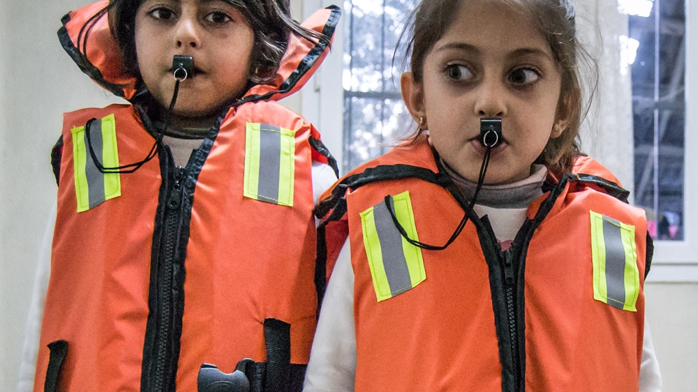 The children try on their life jackets and play with the whistles as though they were toys [Pieter Stockmans/Al Jazeera]
