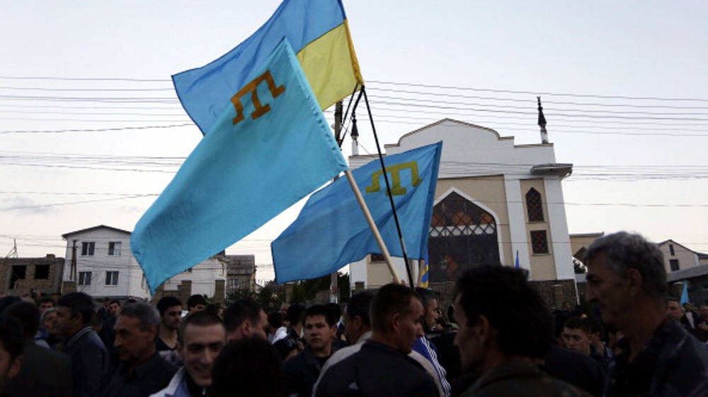 Crimean Tatars hold Ukrainian and Tatar flags as they attend a memorial ceremony marking the 70th anniversary of the deportation of Tatars from Crimea, near a Mosque in Simferopol in 2014 [Getty]