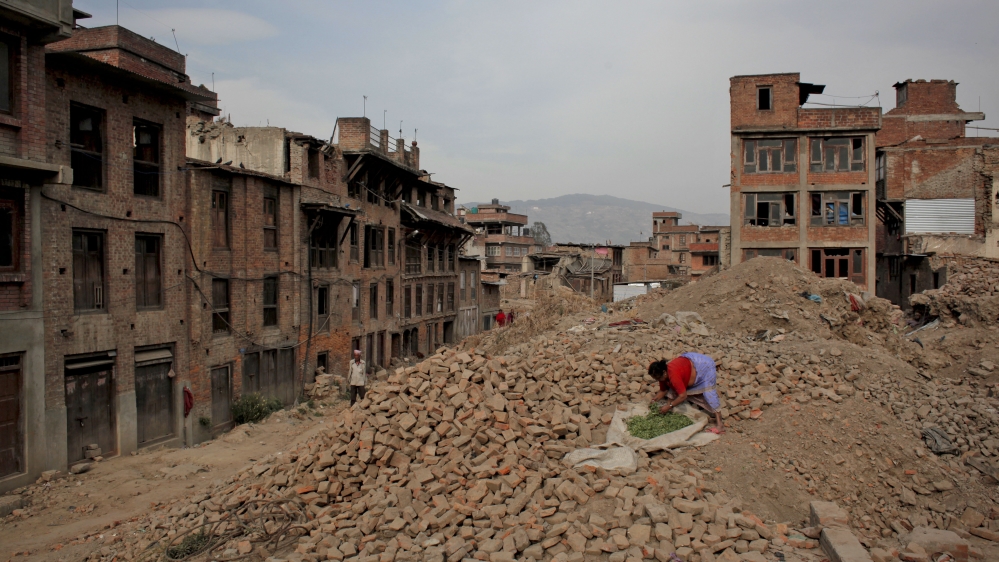 A Nepalese woman dries vegetables on the rubble of houses damaged in last year''s earthquake in Bhaktapu