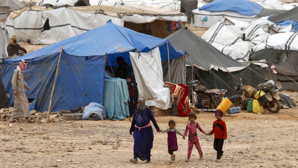 Syrian refugees stuck between the Jordanian and Syrian borders waiting to cross into Jordan, walk at a camp near the town of Ruwaished, at the Hadalat area, east of the capital Amman [REUTERS]