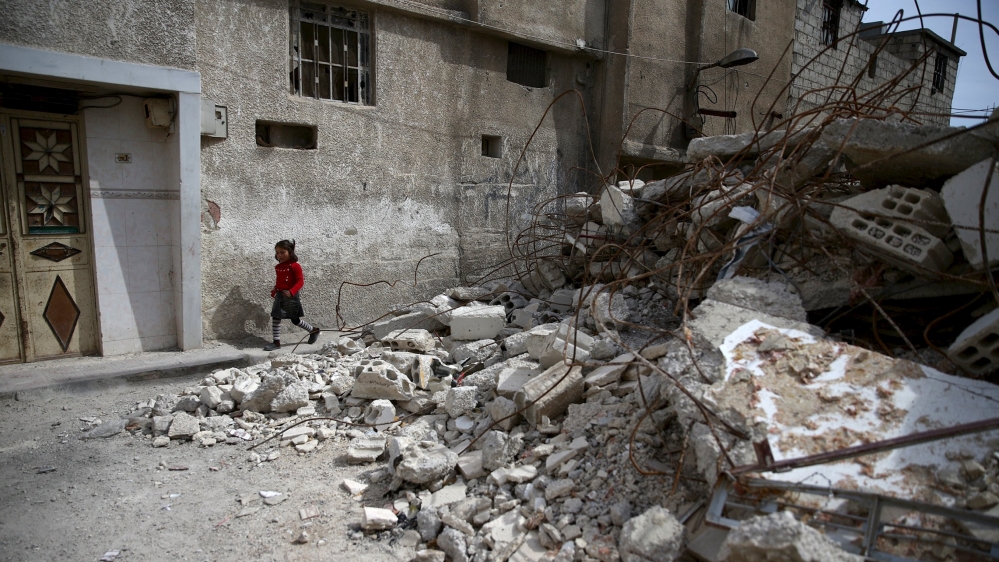 A girl walks near rubble of damaged buildings in the rebel held besieged town of Douma, eastern Damascus suburb of Ghouta