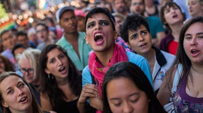 People shout slogans as they gather in front of a makeshift memorial to remember the victims of a mass shooting in Orlando [AP]