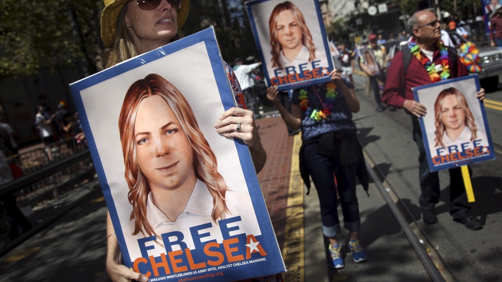 People hold signs calling for the release of imprisoned wikileaks whistleblower Chelsea Manning while marching in a gay pride parade in San Francisco, California