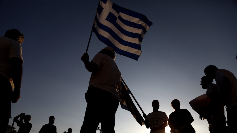 A protester holds a Greek flag as he takes part in an anti-government rally organised to mark a year since Greeks voted against bailout measures in a referendum, in Athens, Greece [EPA]