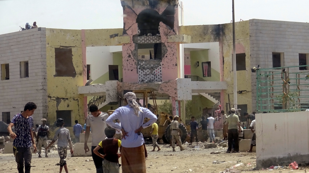 People gather at the scene following an attack by a suicide bomber who drove a car laden with explosives into a compound run by local militias in the port city of Aden, Yemen