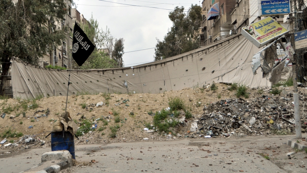 An Islamic State flag is seen near a barricade, which serves as protection from snipers of forces loyal to Syria''s President Bashar al-Assad, in Yarmouk Street, the main street of Yarmouk camp