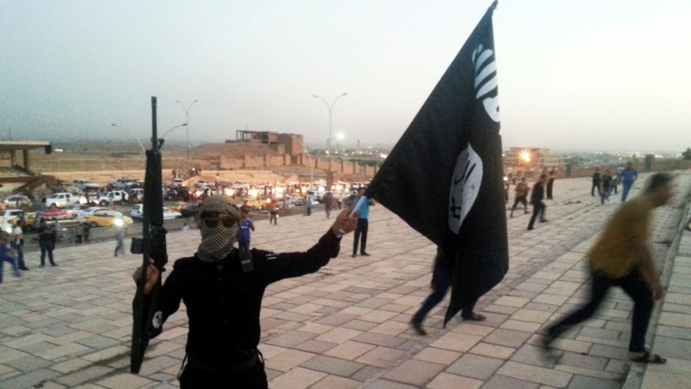 ISIL fighter holds a flag and a weapon on a street in Mosul