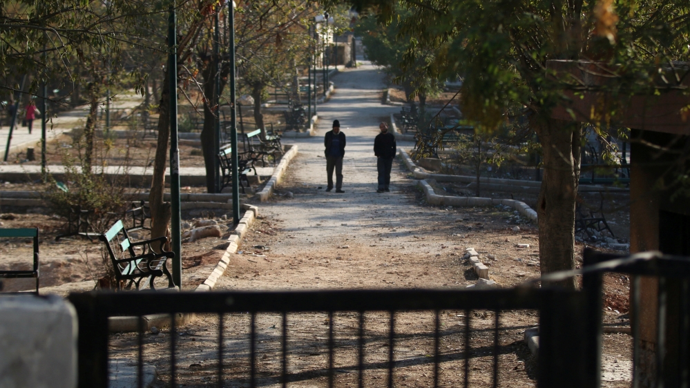 Men walk in a public park in a rebel-held besieged area in Aleppo
