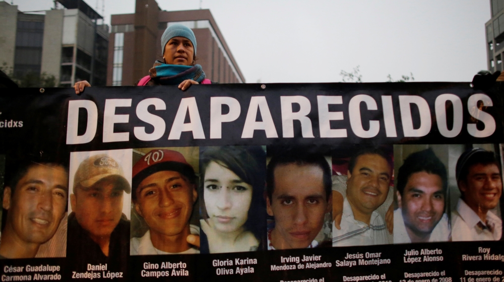 A demonstrator holds a banner with images of her relative and others, who they say went missing or were killed, during a demonstration demanding justice for the victims of violence, in Monterrey