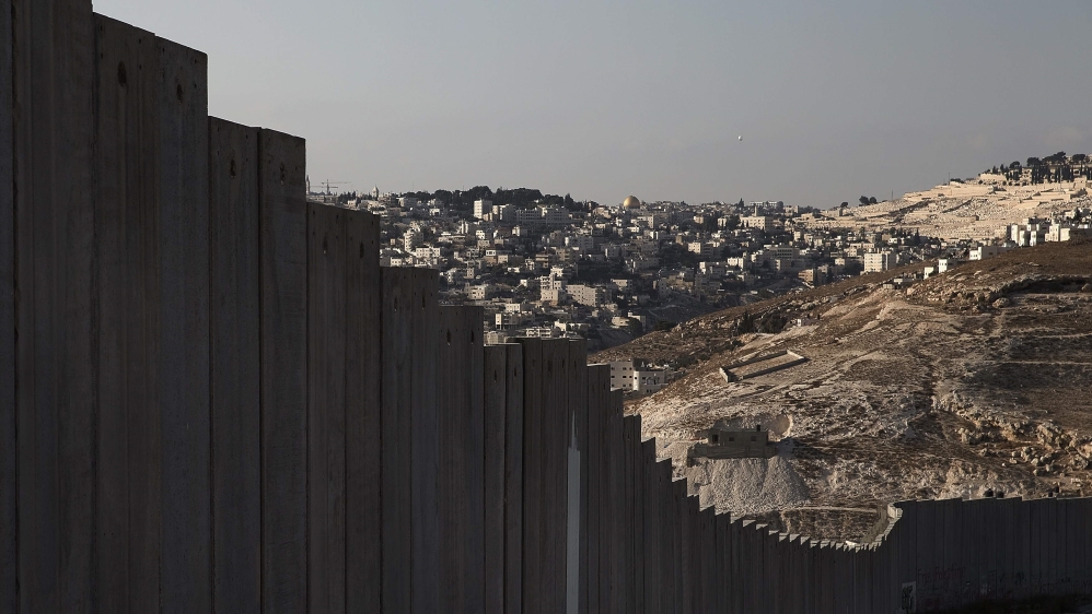 The Dome of the Rock is seen in the distance beyond a section of the controversial Israeli barrier in the West Bank city of Abu Dis