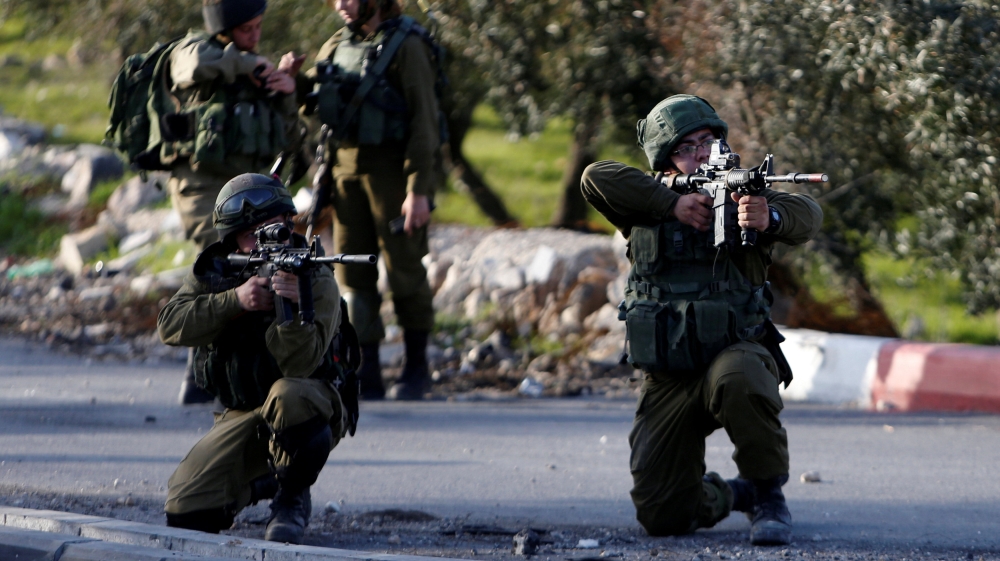 Israeli soldiers aim their weapons towards Palestinian protesters during clashes in the West Bank village of Tuqu near Bethlehem