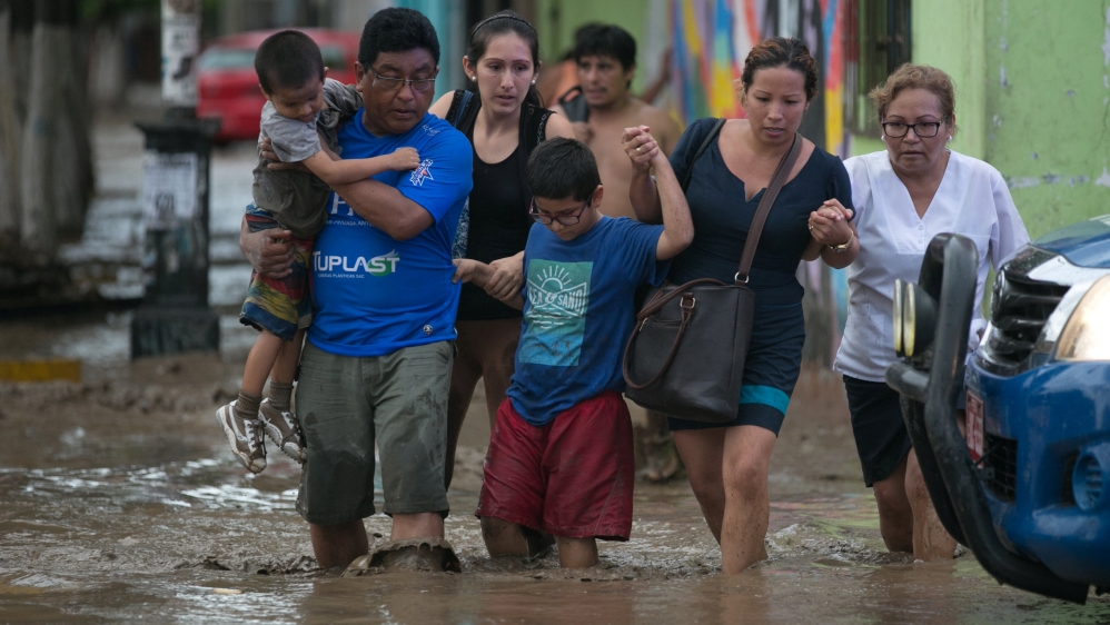 Residents cross a flooded street in Trujillo after deadly floods in Peru