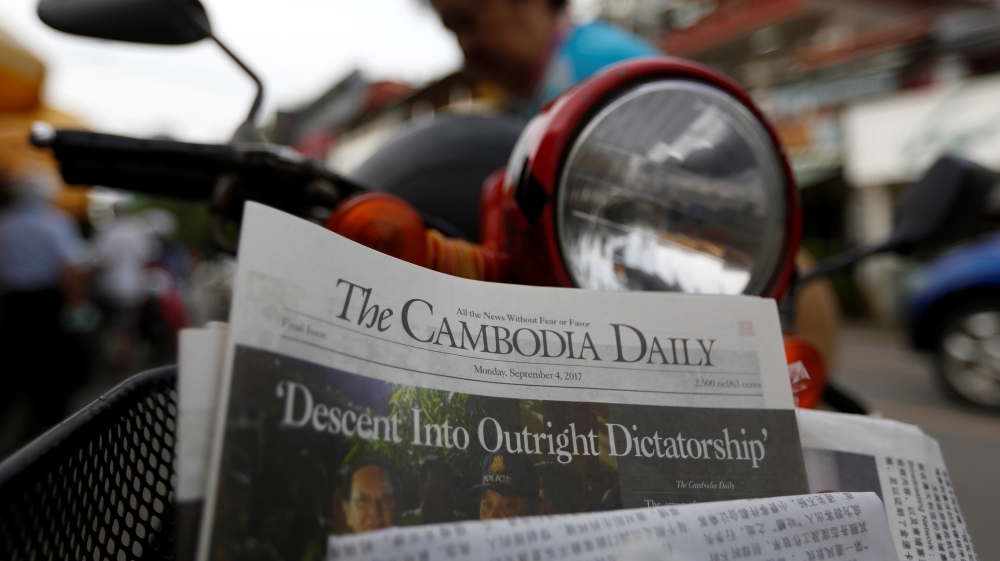 A woman buys the final issue of The Cambodia Daily newspaper at a store along a street in Phnom Penh