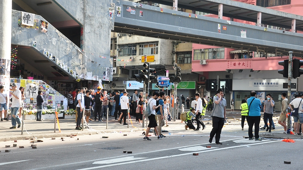Intersection where the shootings took place, showing Lennon Wall and mourning banner for student dead last week [Violet Law/Al Jazeera]