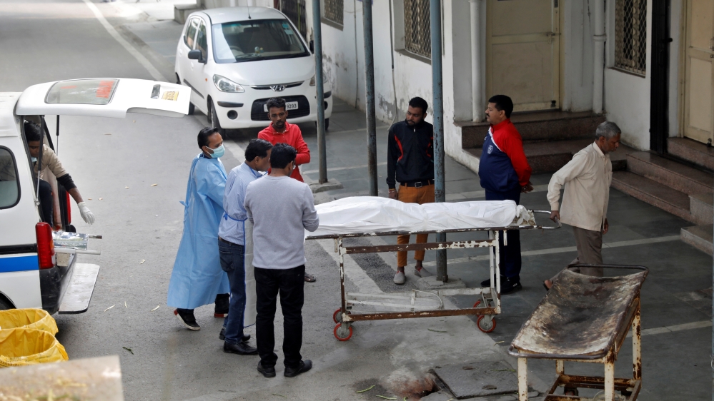 Hospital staff wheel the body of a victim of a fire that swept through a factory where laborers were sleeping, to a mortuary in New Delhi