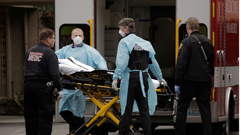 Medics prepare to transfer a patient on a stretcher to an ambulance at the Life Care Center of Kirkland, the long-term care facility linked to the two of three confirmed coronavirus cases in the state