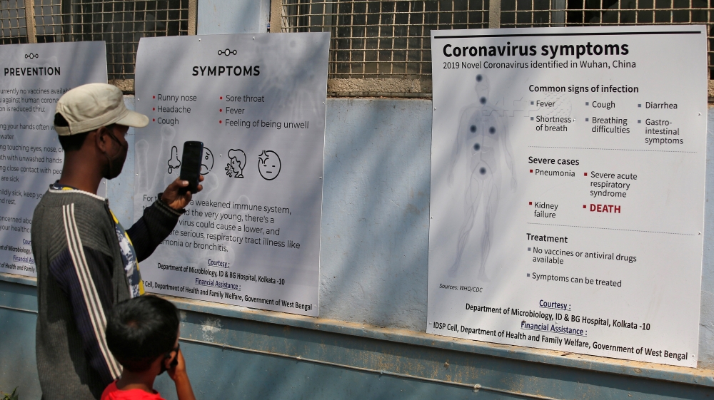 A man uses his mobile phone to take photographs of posters carrying messages on symptoms of coronavirus disease inside hospital premises in Kolkata