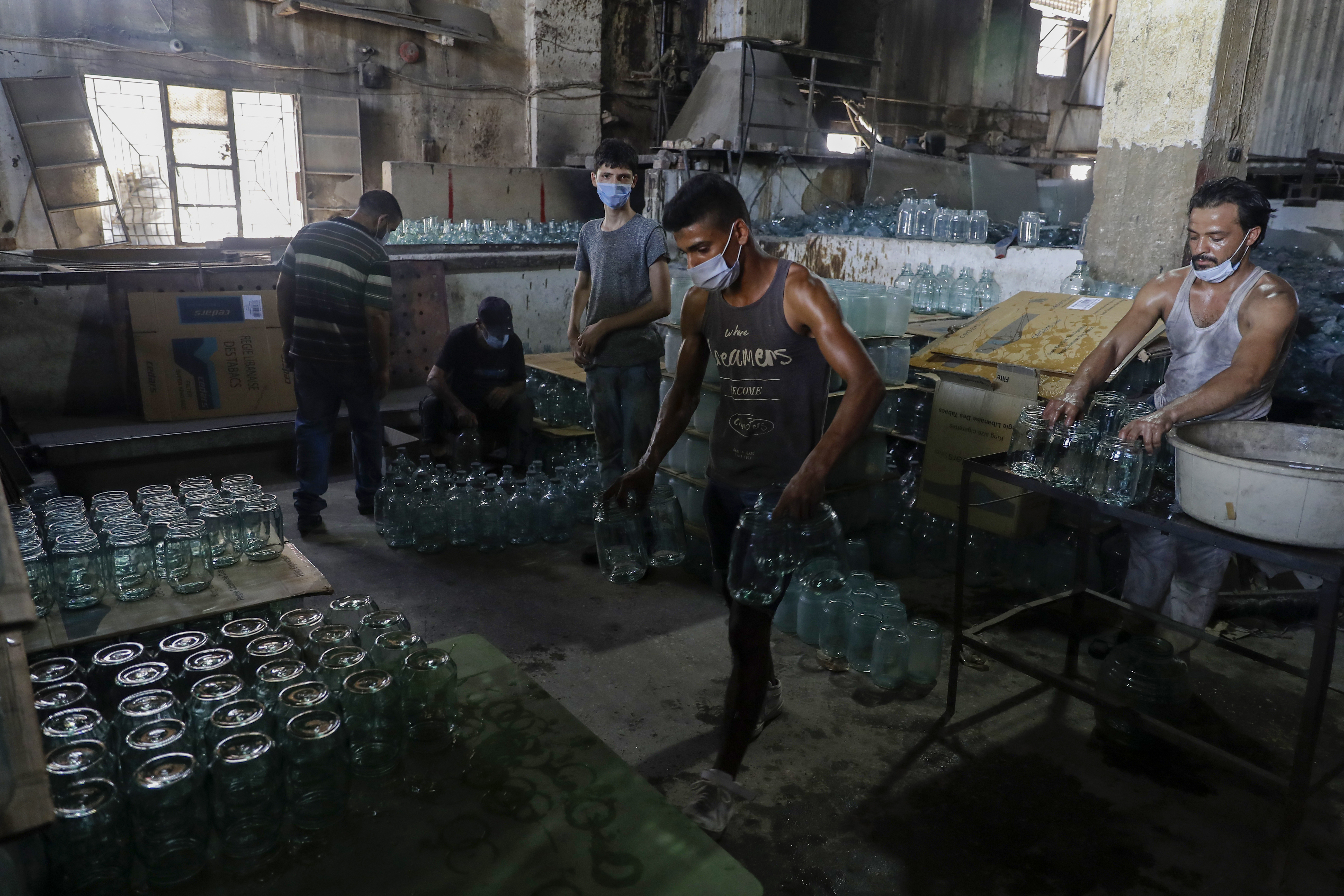 A worker arranges finished jugs at a factory, which is recycling the broken glass as a result of the Beirut explosion, in the northern Lebanese port city of Tripoli on August 25, 2020. The August 4 port explosion ripped through countless glass doors and windows when it laid waste to whole Beirut neighbourhoods [Joseph Eid/AFP]