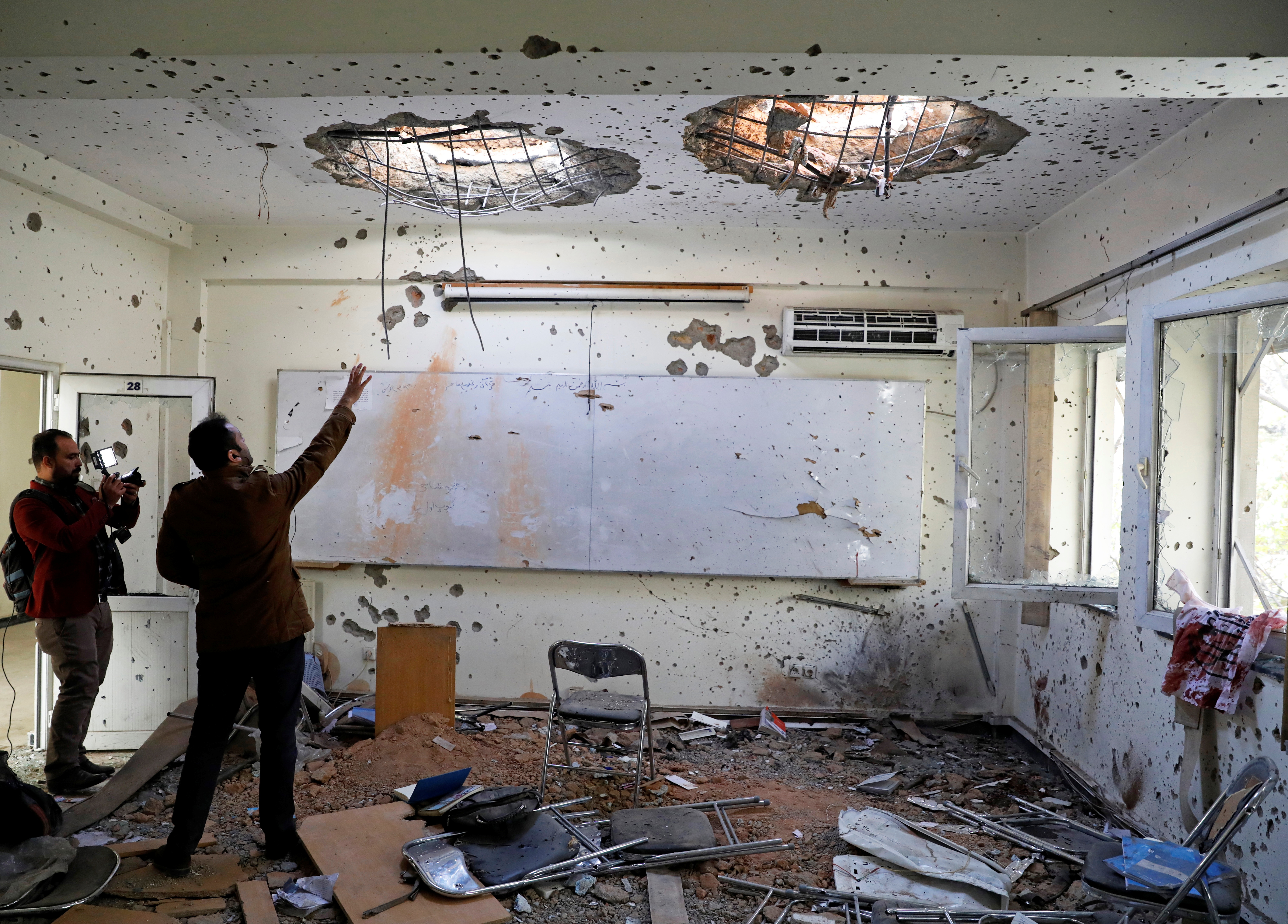 Afghan journalists film inside a classroom after the November 2 attack at the University of Kabul on November 3, 2020 [Mohammad Ismail/Reuters]