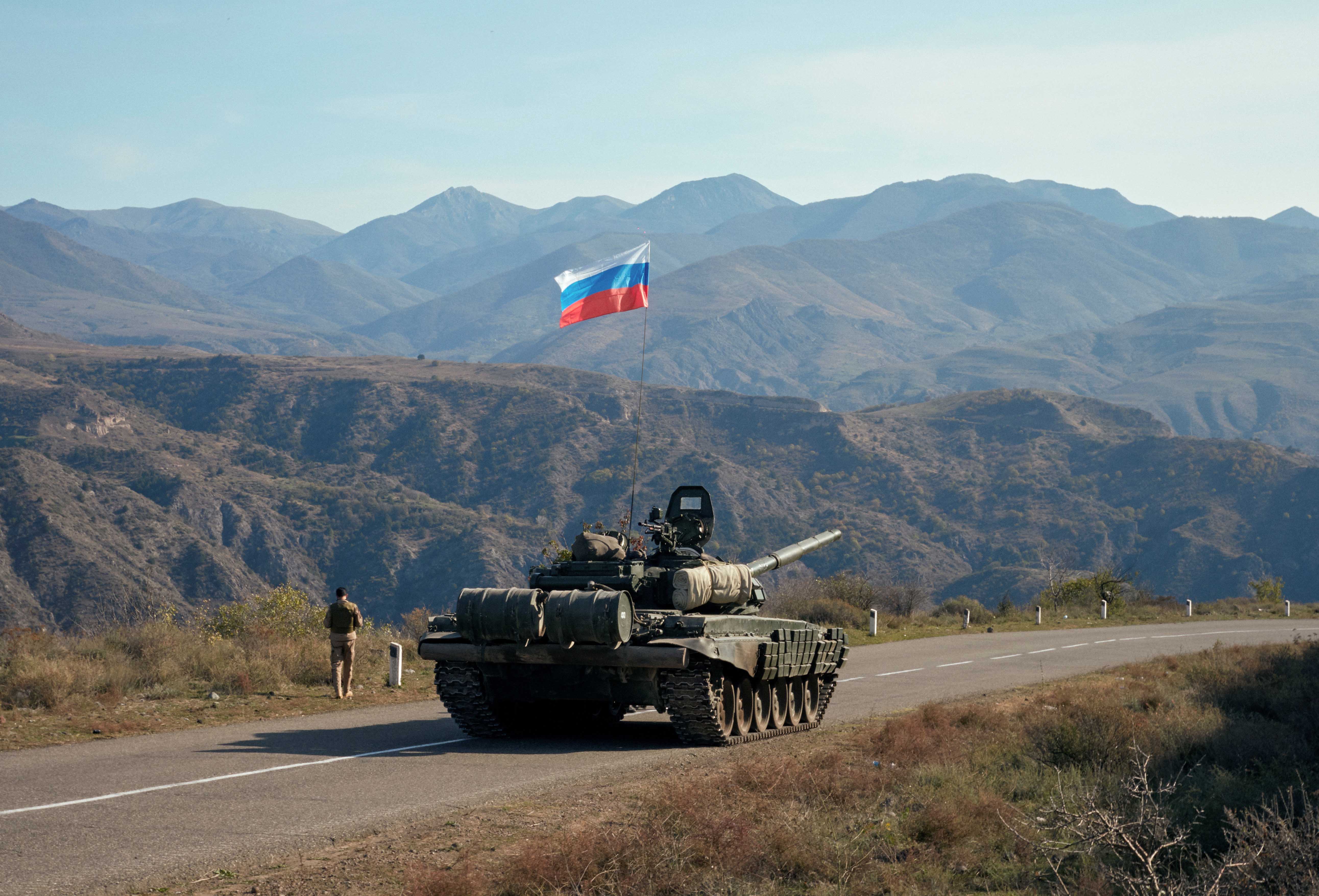 A service member of the Russian peacekeeping troops walks near a tank near the border with Armenia, following the signing of a deal to end the military conflict between Azerbaijan and ethnic Armenian forces, in the region of Nagorno-Karabakh on November 10, 2020 [Reuteres/Francesco Brembati]
